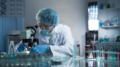 Medical,Lab,Worker,Examining,Laboratory,Glass,With,Sample,Through,Microscope