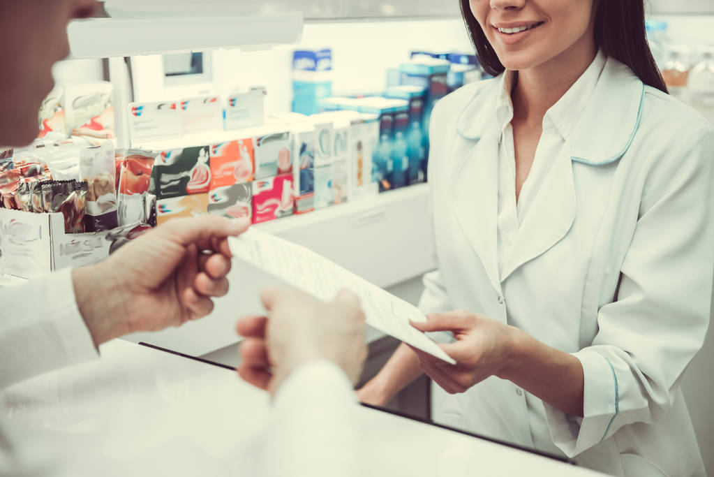 Woman at the pharmacy handing prescription to pharmacist