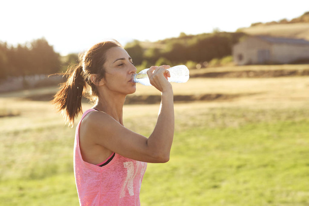 Woman drinking water while exercising